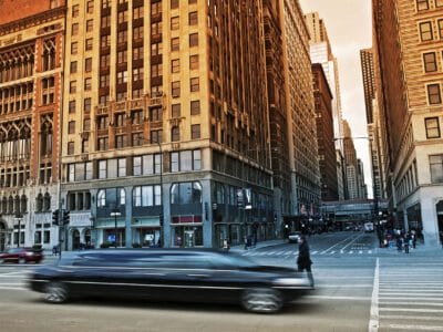 A car driving down the street in front of tall buildings.