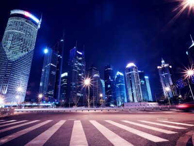 A city street with lights and skyscrapers at night.