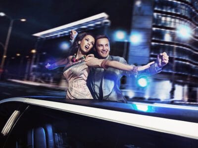 A man and woman are standing in the back of a car.